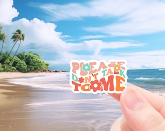May include: A colorful sticker with the text "PLEASE DON'T TALK TO ME" in a retro font. The sticker features flowers and a pastel color palette of pink, orange, green, and blue. The sticker is held in front of a beach scene.