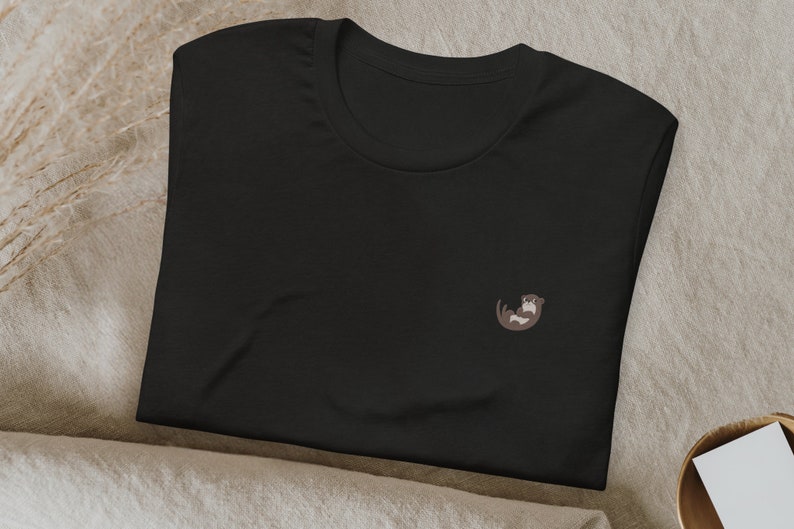 May include: Black t-shirt with a small embroidered otter design.