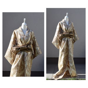 K&ouml;nnte beinhalten: Ein Kimono aus goldenem Brokat mit einer gro&szlig;en goldenen Schleife in der Taille. Der Kimono befindet sich auf einem wei&szlig;en Mannequin vor einem grauen Hintergrund.