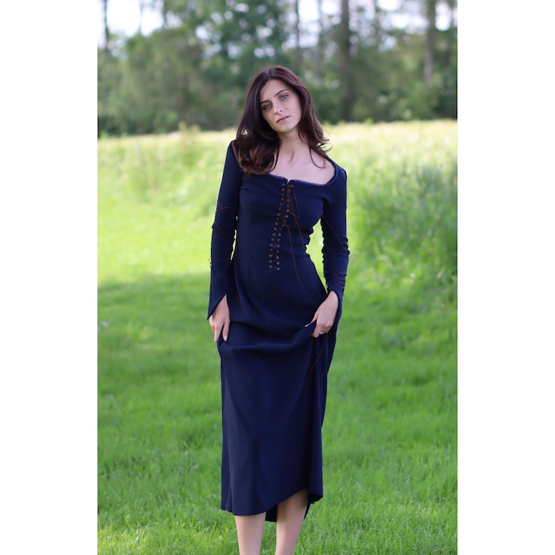 May include: A long-sleeved, dark blue dress with a lace-up bodice and a square neckline. The dress is made of a soft, flowing fabric and has a relaxed fit.