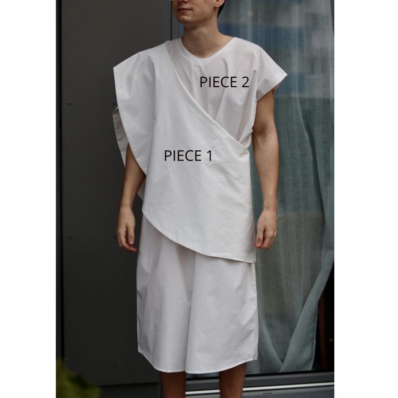 May include: A white, two-piece garment set. Piece 1 is a wrap-style top, and Piece 2 is a short-sleeved top. The outfit is made of a lightweight fabric. The text "PIECE 1" and "PIECE 2" are visible on the garment.