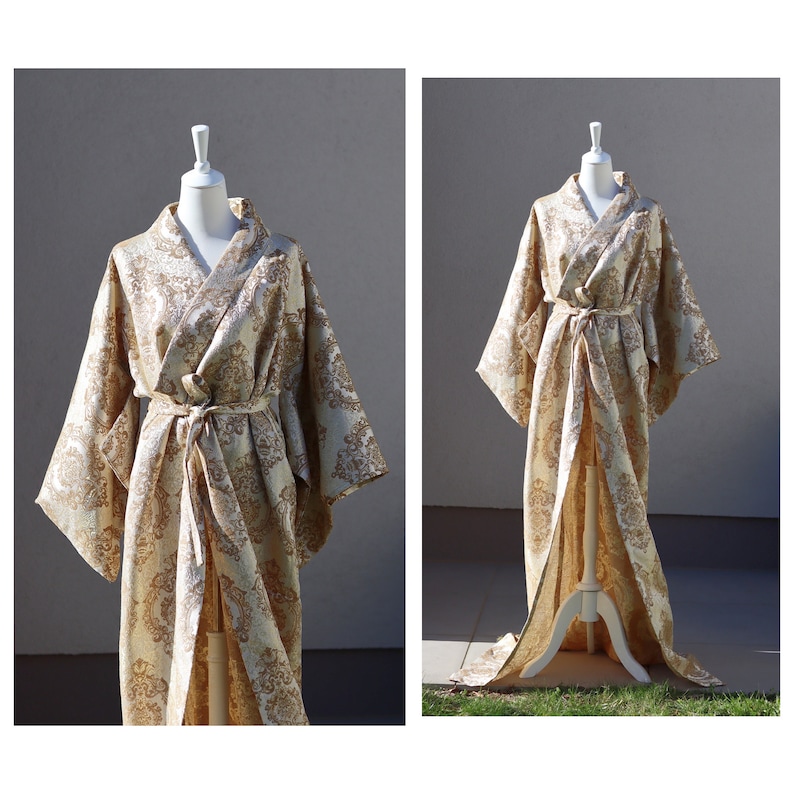 K&ouml;nnte beinhalten: Eine lange, wei&szlig;e und goldene Brokatrobe mit einer weiten, flie&szlig;enden Silhouette. Die Robe hat einen traditionellen japanischen Kimono-Stil mit einem G&uuml;rtel und weiten &Auml;rmeln.
