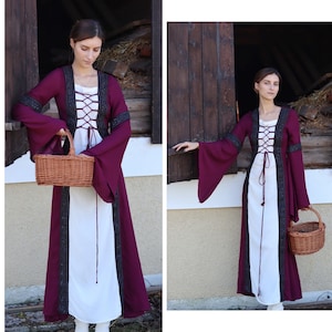May include: A woman wearing a long, white dress with a burgundy overlay and black lace trim. The dress has a lace-up bodice and long sleeves. She is holding a wicker basket.
