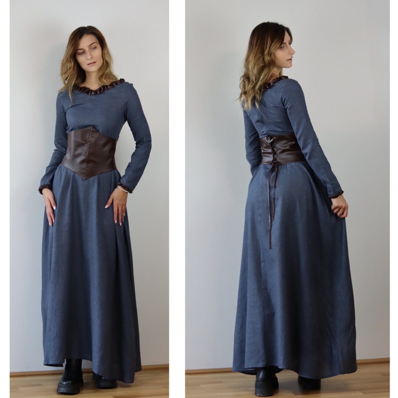 May include: A long, blue dress with a brown leather corset belt. The dress has long sleeves and a ruffled neckline.