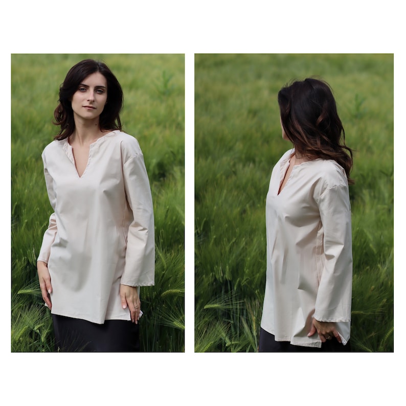 May include: A woman wearing a light beige long-sleeved tunic top with a v-neckline. The top has a relaxed fit and is made of a soft, comfortable fabric.