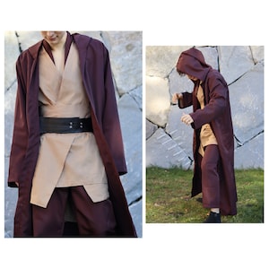 May include: A person wearing a brown and burgundy robe with a brown belt. The robe has a hood and is cinched at the waist. The person is standing in front of a stone wall.