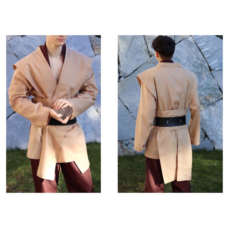 May include: A tan-colored robe with a wide collar and long sleeves. The robe has a belt with a black buckle. The robe is worn over brown pants.