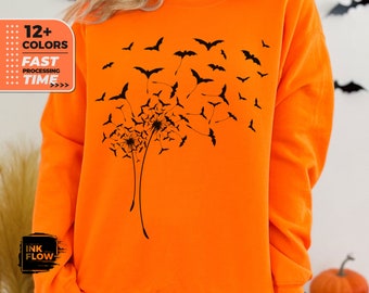 Könnte beinhalten: Leuchtend orangefarbenes Sweatshirt mit einem schwarzen Löwenzahnmotiv und Fledermäusen. Das Sweatshirt hat den Text "12+ COLORS" und "FAST PROCESSING TIME" auf der linken Seite. Ein Halloween-Themen-Kleidungsstück.