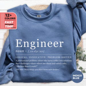 May include: Indigo blue sweatshirt with the word "Engineer" in white, along with a definition and related text. The sweatshirt also has a graphic indicating "12+ COLORS" and "FAST PROCESSING TIME."