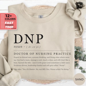 Può includere: Felpa color sabbia con la scritta "DNP" in grandi lettere nere in grassetto. Sotto, è stampata la definizione di "Doctor of Nursing Practice". La felpa presenta anche una grafica che indica "12+ Colori" e "Tempo di elaborazione veloce".