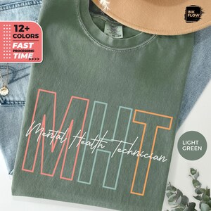 May include: A light green t-shirt with the text "MHT Mental Health Technician" in a colorful outlined font. The text is in a retro style with a light pink, light blue, and orange outline.