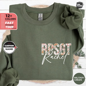 Può includere: Una felpa verde con un design floreale e il testo "RPSGT Rachel" stampato sul davanti.