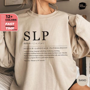 May include: A beige sweatshirt with the text "SLP" and the definition "Speech-Language Pathologist" printed on it. The text is in black.