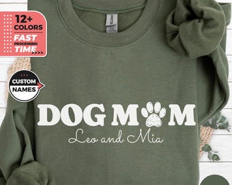 Könnte beinhalten: Ein militärgrüner Pullover mit dem Text "DOG MOM" in Weiß mit einem Pfotenabdruck. Unter dem Text steht "Leo and Mia" in weißer Kursivschrift.