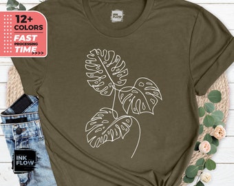 May include: A green t-shirt with a white outline of three monstera leaves. The shirt has a tag that says "Ink Flow".