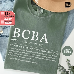 Peut inclure: Un t-shirt vert clair avec le texte "BCBA" en blanc, défini comme "Analyste du comportement certifié par le conseil". Le texte décrit le rôle d'un BCBA, y compris ses compétences et ses responsabilités.