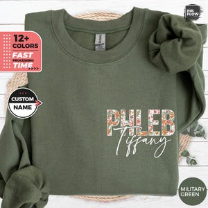 May include: A green sweatshirt with a floral design and the text "PHLEB Tiffany" printed on the front. The sweatshirt is a popular style for casual wear.