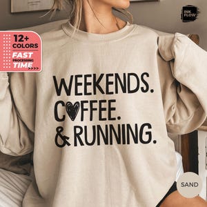 May include: A beige sweatshirt with the text "Weekends. Coffee. & Running." printed in black. The text includes a small heart symbol next to the word "Coffee."