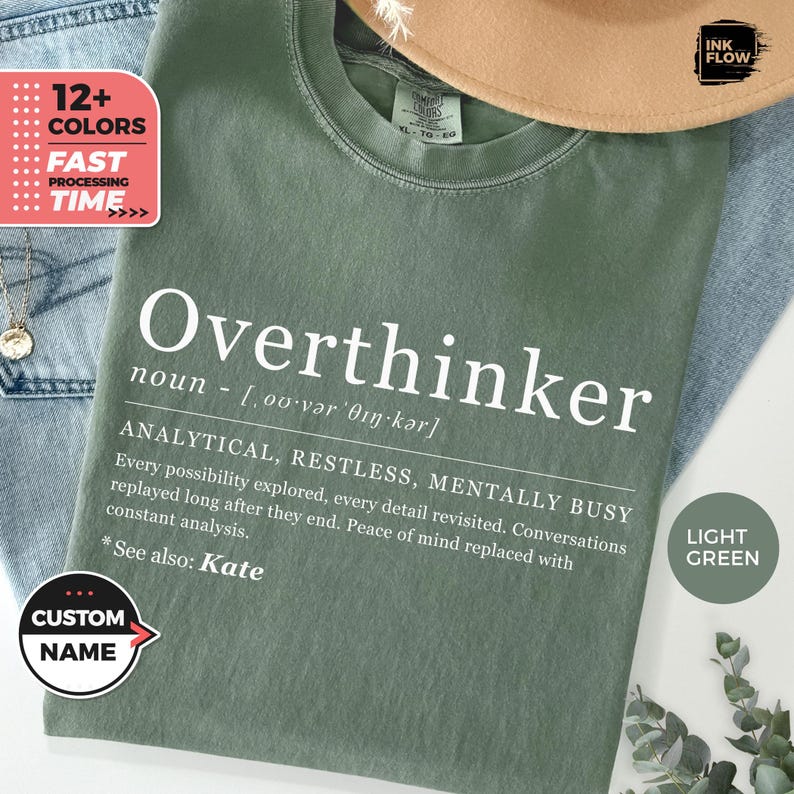May include: A light green t-shirt with the word "Overthinker" in white, along with a definition. The shirt also features the text "ANALYTICAL, RESTLESS, MENTALLY BUSY" and "See also: Kate". A "Custom Name" button is visible.
