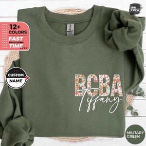 Peut inclure: Un sweat-shirt vert militaire avec un motif floral qui épelle "BCBA Tiffany".