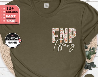 May include: A heather olive t-shirt with a floral design spelling out "FNP" and the name "Tiffany" underneath.