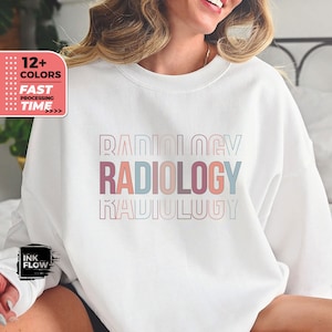 May include: White sweatshirt with the word "RADIOLOGY" printed in stacked, colourful letters. The letters are outlined in a light blue, pink and peach colour.