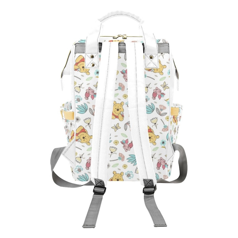 May include: White canvas backpack with a Winnie the Pooh and Piglet print. The backpack has adjustable straps and a top handle.