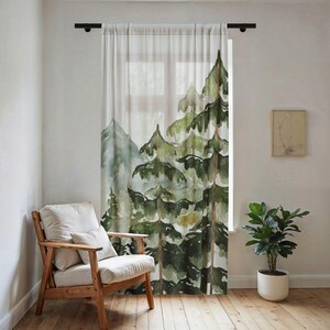 May include: A sheer window curtain featuring a watercolor print of a forest with tall green pine trees and distant mountains in shades of sage and forest green against a white background, hanging from a black rod over a window.