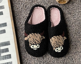 Puede incluir: Un letrero de madera con la palabra "COFFEE" en letras negras sobre fondo blanco.  El letrero está enmarcado en madera marrón.  Dos pantuflas de felpa negras con un diseño de cara de vaca marrón están sobre una alfombra marrón.  Un pequeño letrero de madera con el texto "Stay Humble Hustle Hard" está en la esquina superior derecha de la imagen.  Una pequeña figura de búho de cerámica está en la esquina superior derecha de la imagen.