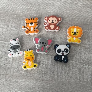 May include: Set of eight colorful animal-shaped silicone buttons. The animals include a zebra, tiger, monkey, lion, elephant, giraffe, and panda.