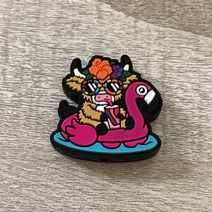 May include: A brown and white cow wearing sunglasses and a flower crown floats on a pink flamingo pool float. The cow is holding a pink and purple drink.