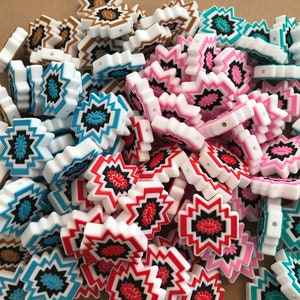 May include: A large pile of colorful silicone beads with a geometric pattern. The beads are white with black, red, pink, blue, and brown accents.