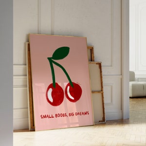 K&ouml;nnte beinhalten: Ein rosa gerahmter Druck mit einer Grafik von zwei roten Kirschen und dem Text "SMALL BOOBS, BIG DREAMS".
