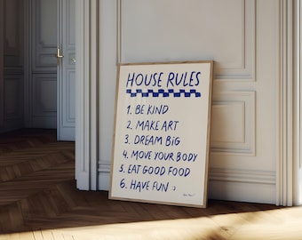 以下が含まれることがあります： 白い額縁に入ったポスターに、青い文字で「HOUSE RULES」と書かれています。ポスターには6つのルールが書かれています。親切に、芸術を作り、大きく夢を見て、体を動かし、おいしいものを食べ、楽しんでください。ポスターは白い壁に立てかけられています。