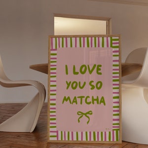 May include: A framed pink and green striped poster with the text "I love you so matcha" in green lettering and a green bow.