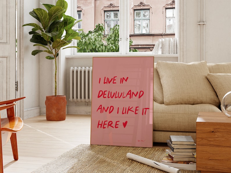 以下が含まれることがあります： 赤い文字で「I live in Delululand and I like it here &hearts;」と書かれたピンクのポスターです。