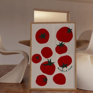 May include: A framed art print featuring a collection of red tomatoes with green stems against a white background. The tomatoes vary in size and are arranged in a visually appealing composition. The print is in a light wood frame.