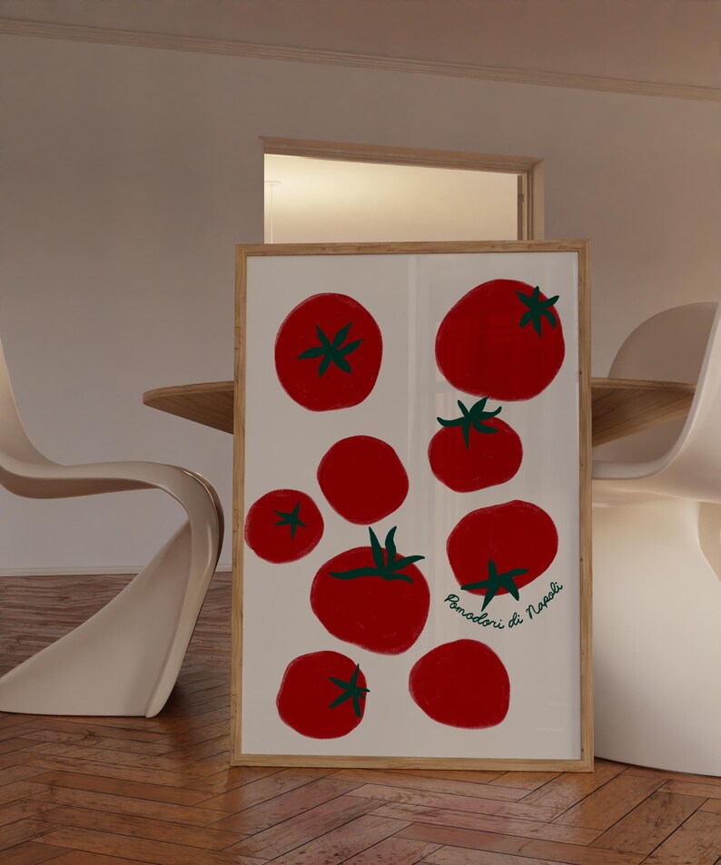 May include: A framed art print featuring a collection of red tomatoes with green stems against a white background. The tomatoes vary in size and are arranged in a visually appealing composition. The print is in a light wood frame.