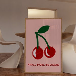 K&ouml;nnte beinhalten: Ein gerahmtes rosa Poster mit einem gr&uuml;nen Stiel und zwei roten Kirschen. Der Text "SMALL BOOBS, BIG DREAMS" ist unter den Kirschen gedruckt.