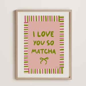 May include: A framed print with pink and green stripes, featuring the text "I love you so matcha" and a green bow.