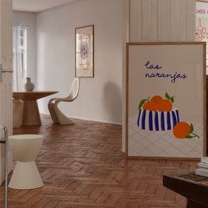 May include: A framed print with a white background and a blue and white striped bowl filled with orange fruit. The text "las naranjas" is written in cursive above the bowl.