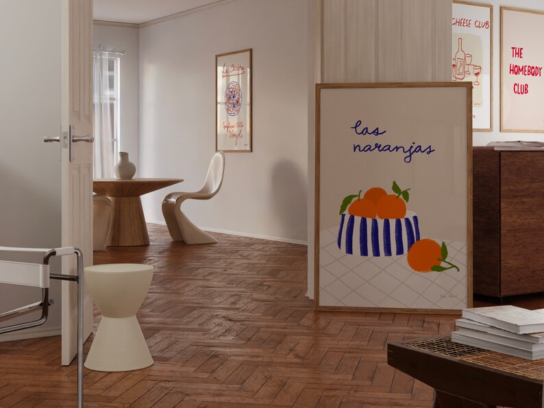 May include: A framed print with a white background and a blue and white striped bowl filled with orange fruit. The text "las naranjas" is written in cursive above the bowl.