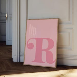 May include: A framed pink poster with a large pink letter "R" in the center.