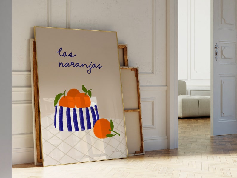 May include: A framed print with a light brown background featuring a blue and white striped bowl filled with orange oranges. The text "las naranjas" is written in black cursive above the bowl.