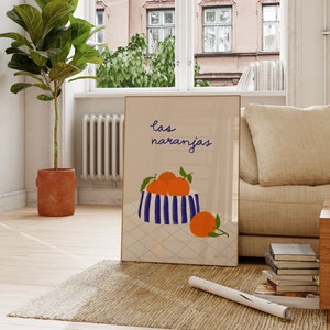 May include: A framed print with a blue and white striped bowl filled with orange fruit. The text "las naranjas" is written in black above the bowl.