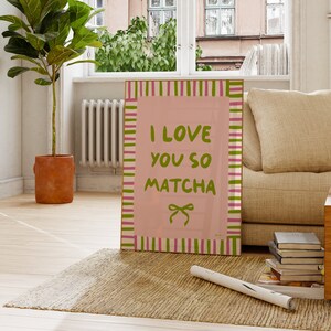 May include: Pink and green striped poster with the text "I love you so matcha" in green letters. The poster has a pink ribbon with a bow on it.