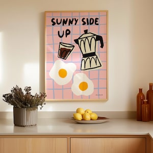 Puede incluir: Una impresión ilustrada rosa y blanca con el texto "Sunny Side Up" y imágenes de una cafetera, un vaso de café y dos huevos fritos.
