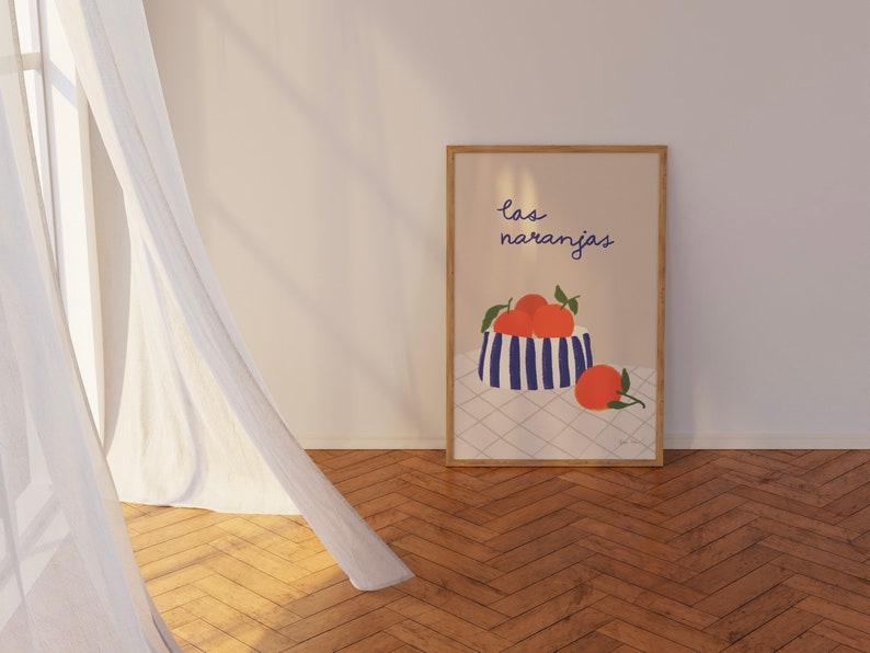 May include: A framed print with a blue and white striped bowl filled with orange fruit. The text "las naranjas" is written in blue above the bowl. The print is on a white background with a checkered pattern.