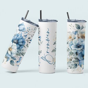 May include: Three stainless steel tumblers with a white background and blue floral designs. The tumbler in the centre has the name "Brooklyn" written in cursive on it.