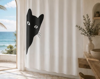 May include: A white shower curtain featuring a large, black graphic of a cat head peeking from the left side. The cat has pointed ears, almond-shaped eyes, and visible whiskers. The curtain hangs from a simple rod with metal rings at the top.